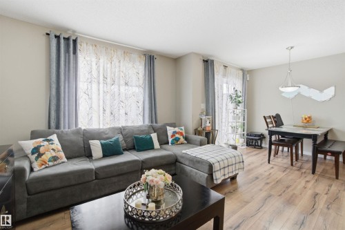 Living room with wide plank flooring, a large window with sheer and blackout curtains, and neutral wall tones - 13905 138 St, Edmonton, AB - Indoor Photo Showing Living Room