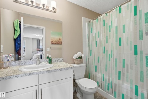 The bathroom features a vanity with a white countertop and an integrated sink, illuminated by a four-light fixture above the mirror - 13905 138 St, Edmonton, AB - Indoor Photo Showing Bathroom