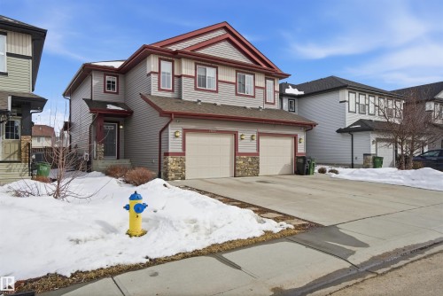 The property features a two-story exterior with grey siding and red trim, complemented by stone accents - 13905 138 St, Edmonton, AB - Outdoor With Facade