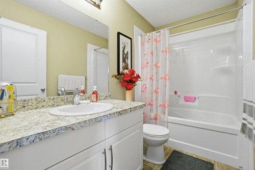 This bathroom features a vanity with a granite countertop and a white sink, a mirror, and a full-size bathtub with a shower - 13905 138 St, Edmonton, AB - Indoor Photo Showing Bathroom