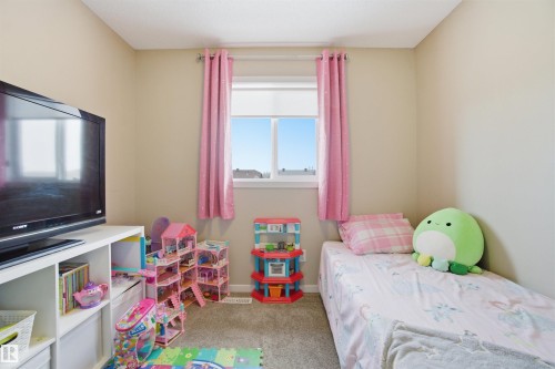 This room features neutral-toned walls, a window with pink curtains providing natural light, and carpeted flooring - 13905 138 St, Edmonton, AB - Indoor Photo Showing Bedroom