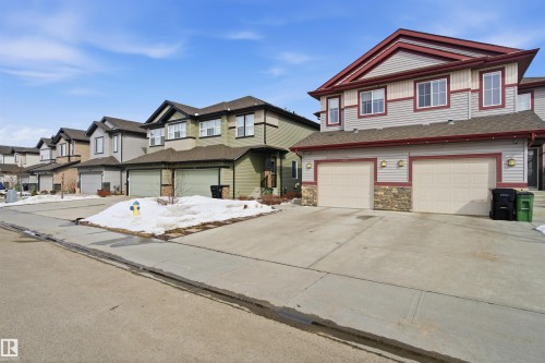 The property features a two-story exterior with light-colored siding, red trim, and stone accents - 13905 138 St, Edmonton, AB - Outdoor With Facade