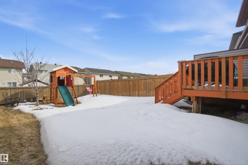 The property features a fenced backyard with a wooden deck and a playground structure - 13905 138 St, Edmonton, AB - Outdoor With Deck Patio Veranda