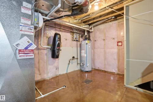 The property includes a utility area with exposed ceiling joists and pipes, a water heater, and a floor drain - 13905 138 St, Edmonton, AB - Indoor Photo Showing Basement