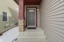 The property features a front entrance with a grey door, a stone-accented pillar, and siding in a muted tone - 13905 138 St, Edmonton, AB  - Outdoor With Exterior 