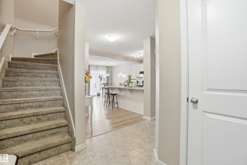 Entryway featuring a carpeted staircase with a white railing, tile flooring, and a white interior door - 13905 138 St, Edmonton, AB - Indoor Photo Showing Other Room