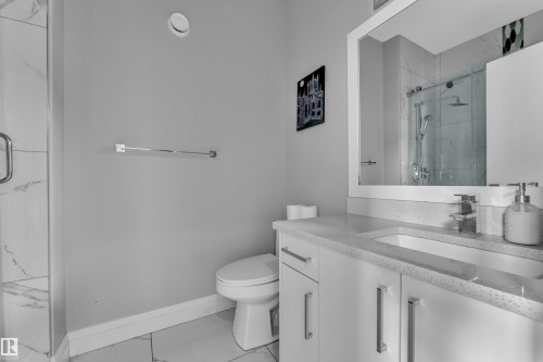 Bathroom featuring a modern vanity with integrated sink, stone-finish countertop, and chrome fixtures - 3702 Claxton Place, Edmonton, AB - Indoor Photo Showing Bathroom