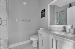 Bathroom featuring a modern vanity with integrated sink, stone-finish countertop, and chrome fixtures - 