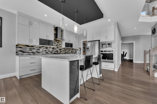 Contemporary kitchen featuring white flat-panel cabinetry, a multi-tone mosaic tile backsplash, and stainless steel appliances - 3702 Claxton Place, Edmonton, AB - Indoor Photo Showing Kitchen With Upgraded Kitchen