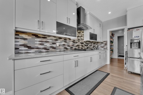 Modern kitchen featuring white cabinetry, light-toned countertops, and a multi-toned hexagonal tile backsplash - 3702 Claxton Place, Edmonton, AB - Indoor Photo Showing Kitchen With Upgraded Kitchen