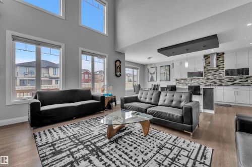 Open-concept living space featuring high ceilings, wood-finish flooring, and multiple large windows - 3702 Claxton Place, Edmonton, AB - Indoor Photo Showing Living Room