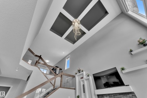 Two-story living area featuring a vaulted ceiling with a coffered design, a contemporary chandelier, and an expansive skylight - 3702 Claxton Place, Edmonton, AB - Indoor Photo Showing Other Room