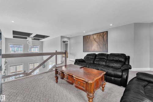 Carpeted upper-level landing with glass and wood railing overlooking the lower level - 3702 Claxton Place, Edmonton, AB - Indoor Photo Showing Living Room