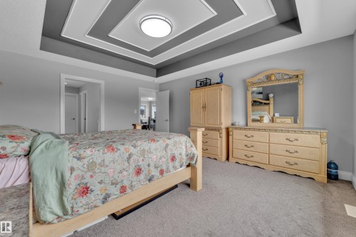 Bedroom featuring a tiered tray ceiling with recessed lighting, light gray wall paint, and gray carpeting - 3702 Claxton Place, Edmonton, AB - Indoor Photo Showing Bedroom