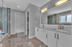 Double vanity with integrated sinks, quartz-finish countertops, and under-mirror lighting - 