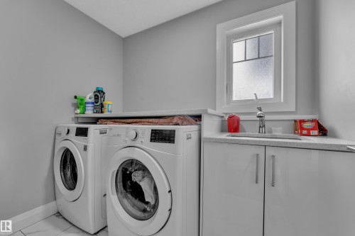 Dedicated laundry area featuring a utility sink, white cabinetry with brushed nickel pulls, and a window with frosted glass - 3702 Claxton Place, Edmonton, AB - Indoor Photo Showing Laundry Room