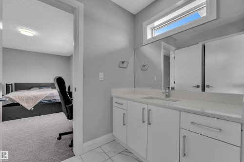 Contemporary bathroom vanity featuring a light-colored countertop, integrated sink, and white cabinetry with brushed nickel hardware - 3702 Claxton Place, Edmonton, AB - Indoor Photo Showing Bathroom