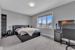 Bedroom featuring light gray walls, textured gray carpeting, a large window with white trim, and a flush-mount ceiling light - 