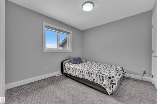 Bedroom featuring light gray walls, gray patterned carpeting, a white trim package, and a double-pane window with white framing - 3702 Claxton Place, Edmonton, AB - Indoor Photo Showing Bedroom