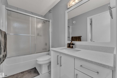 Bathroom featuring a white vanity with a speckled countertop, undermount sink, and a framed mirror - 3702 Claxton Place, Edmonton, AB - Indoor Photo Showing Bathroom