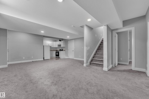 Expansive finished lower level featuring recessed lighting, a full-height carpeted staircase, and multiple white paneled doors - 3702 Claxton Place, Edmonton, AB - Indoor Photo Showing Other Room