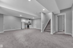 Expansive finished lower level featuring recessed lighting, a full-height carpeted staircase, and multiple white paneled doors - 