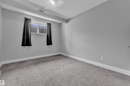 Room featuring light gray walls, gray patterned carpet, a single window with blinds and dark curtains, white baseboards, and a flush mount ceiling light - 3702 Claxton Place, Edmonton, AB - Indoor Photo Showing Other Room