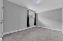 Carpeted room featuring light gray walls, white baseboards, and a white ceiling with a flush-mount light fixture - 