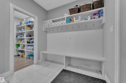 Mudroom featuring a built-in bench, wall-mounted hooks, and overhead shelving - 