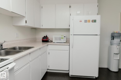 Kitchen featuring white cabinetry, a double basin stainless steel sink, and light-colored countertops - 42 11245 31 Avenue, Edmonton, AB - Indoor Photo Showing Kitchen With Double Sink