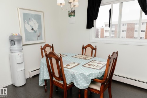 Dining area featuring dark flooring, white walls, and a large window with white trim - 42 11245 31 Avenue, Edmonton, AB - Indoor Photo Showing Dining Room