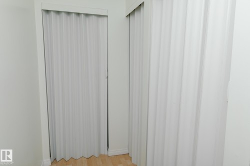 The property features light wood flooring and white accordion-style doors, providing a clean aesthetic - 42 11245 31 Avenue, Edmonton, AB - 