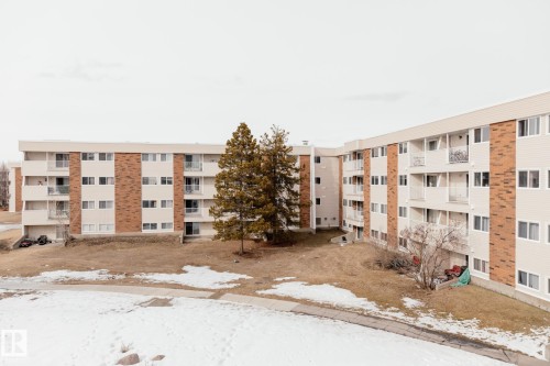 The property features multi-story buildings with balconies, brick and siding facades, and mature trees on the grounds - 42 11245 31 Avenue, Edmonton, AB - Outdoor With Balcony With Facade