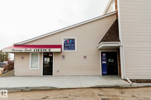 The property features a light-colored siding exterior, multiple entry points, and a prominent red awning over the main entrance - 42 11245 31 Avenue, Edmonton, AB - Outdoor