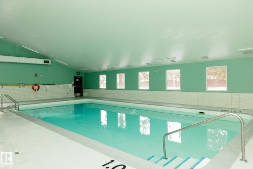 Indoor swimming pool featuring a vaulted ceiling, light green walls, and several windows - 42 11245 31 Avenue, Edmonton, AB - Indoor Photo Showing Other Room With In Ground Pool