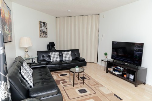 Living area featuring light-toned flooring, white walls, and a light-colored accordion-style room divider - 42 11245 31 Avenue, Edmonton, AB - Indoor Photo Showing Living Room