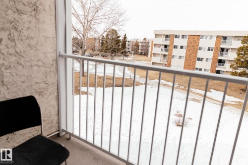 The property features a private balcony with a metal railing, overlooking a snow-covered ground with sparse trees and distant buildings - 42 11245 31 Avenue, Edmonton, AB - Outdoor With Balcony