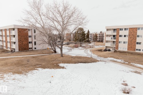 View of the property's exterior, featuring a multi-story building with white siding and brick accents - 42 11245 31 Avenue, Edmonton, AB - Outdoor With Balcony