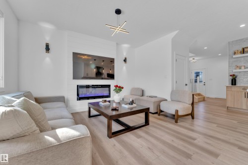 Open-concept living area featuring light wood-finish flooring, a contemporary electric fireplace with a shiplap surround, and recessed ceiling lighting - 9 Hunter Place, Spruce Grove, AB - Indoor Photo Showing Living Room