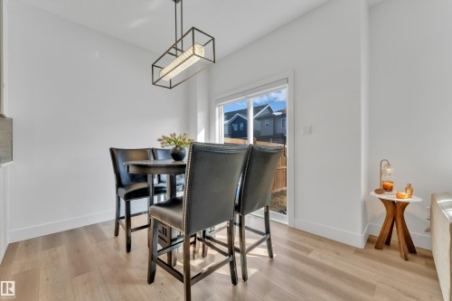 Dining area featuring wood-finish flooring, a rectangular light fixture with embedded crystals, and a glass-paneled exterior door - 9 Hunter Place, Spruce Grove, AB - Indoor Photo Showing Dining Room