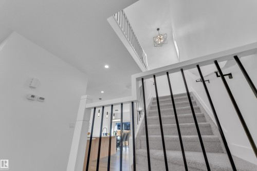 Staircase featuring light gray carpeted treads and risers, black vertical balusters, and a white handrail - 9 Hunter Place, Spruce Grove, AB - Indoor Photo Showing Other Room
