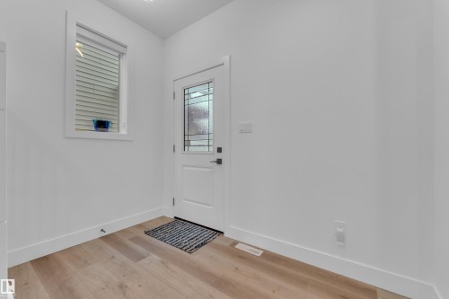 Entryway featuring a white door with decorative glass inserts, a single window with blinds, wood-finish flooring, recessed lighting, and crisp white walls - 9 Hunter Place, Spruce Grove, AB - Indoor Photo Showing Other Room