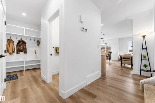 Entryway featuring wood-finish flooring, a built-in storage bench, open shelving, shaker-style doors with matte black hardware, and an adjacent powder room - 9 Hunter Place, Spruce Grove, AB - Indoor Photo Showing Other Room