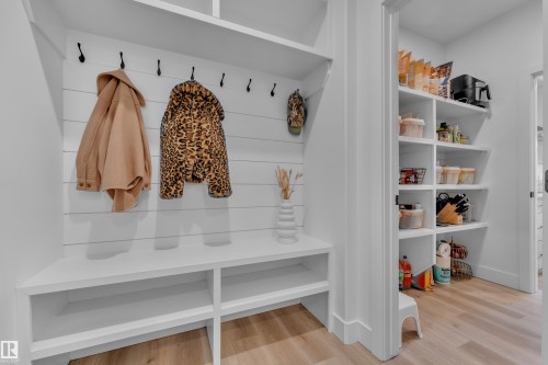 Built-in mudroom bench with open shelving, integrated coat hooks, and shiplap wall paneling - 9 Hunter Place, Spruce Grove, AB - Indoor