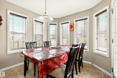 Dining area featuring multiple large windows with white trim, ceramic tile flooring, and a ceiling-mounted pendant light fixture - 8922 5Av, Edmonton, AB - Indoor Photo Showing Dining Room
