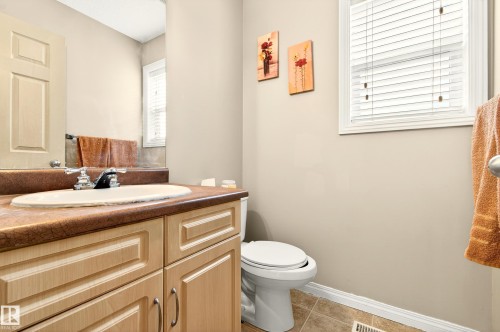 Bathroom vanity with light wood-finish cabinetry, a drop-in sink, and a contrasting countertop - 8922 5Av, Edmonton, AB - Indoor Photo Showing Bathroom