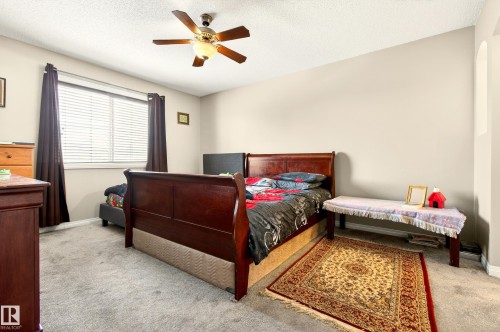 Carpeted bedroom featuring a ceiling fan with light fixture, window with blinds and dark curtains, and a light-colored wall finish - 8922 5Av, Edmonton, AB - Indoor Photo Showing Bedroom