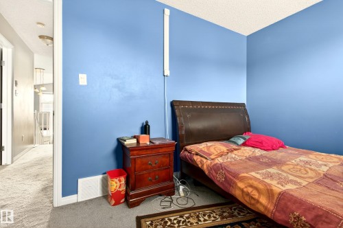 Carpeted room with blue painted walls, white baseboards, and a textured ceiling - 8922 5Av, Edmonton, AB - Indoor Photo Showing Bedroom