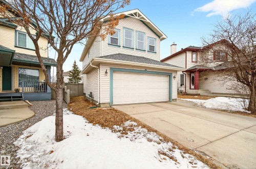 Two-story home featuring light-colored siding with blue trim accents and a pitched roof - 8922 5Av, Edmonton, AB - Outdoor