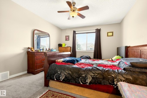 Room featuring light-toned walls, grey carpet flooring, and a ceiling fan with light fixture - 8922 5Av, Edmonton, AB - Indoor Photo Showing Bedroom